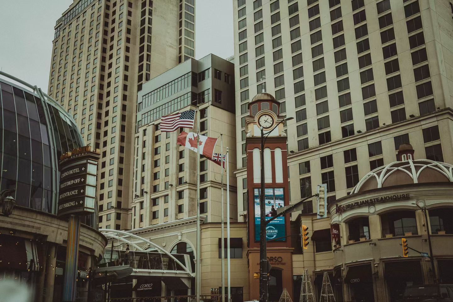 Clock tower and hotel towers on an overcast day at Niagara Falls, with Canadian, American, and British flags.